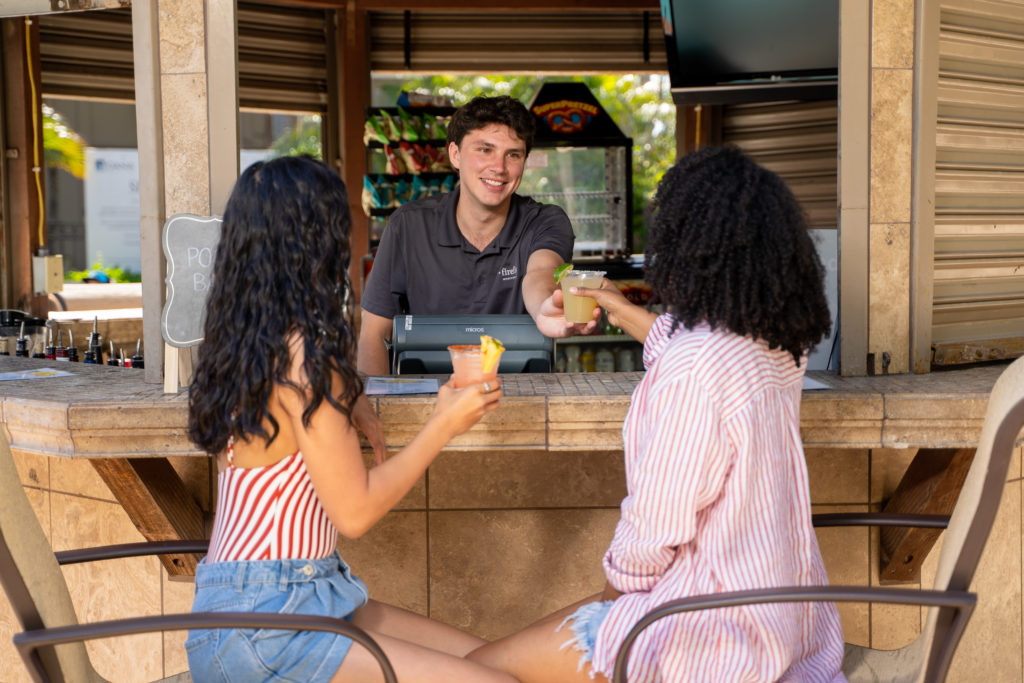 bartender handing girl drink at Pool Bar