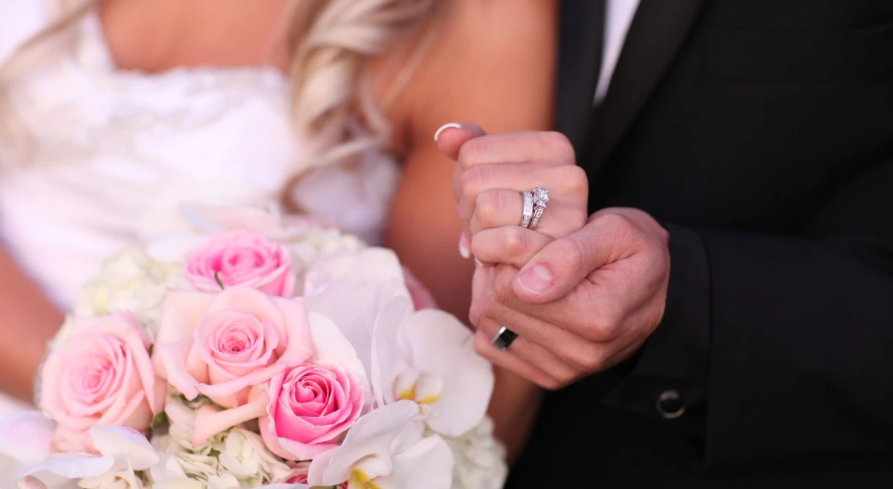 Couple holding hands behind a bouquet