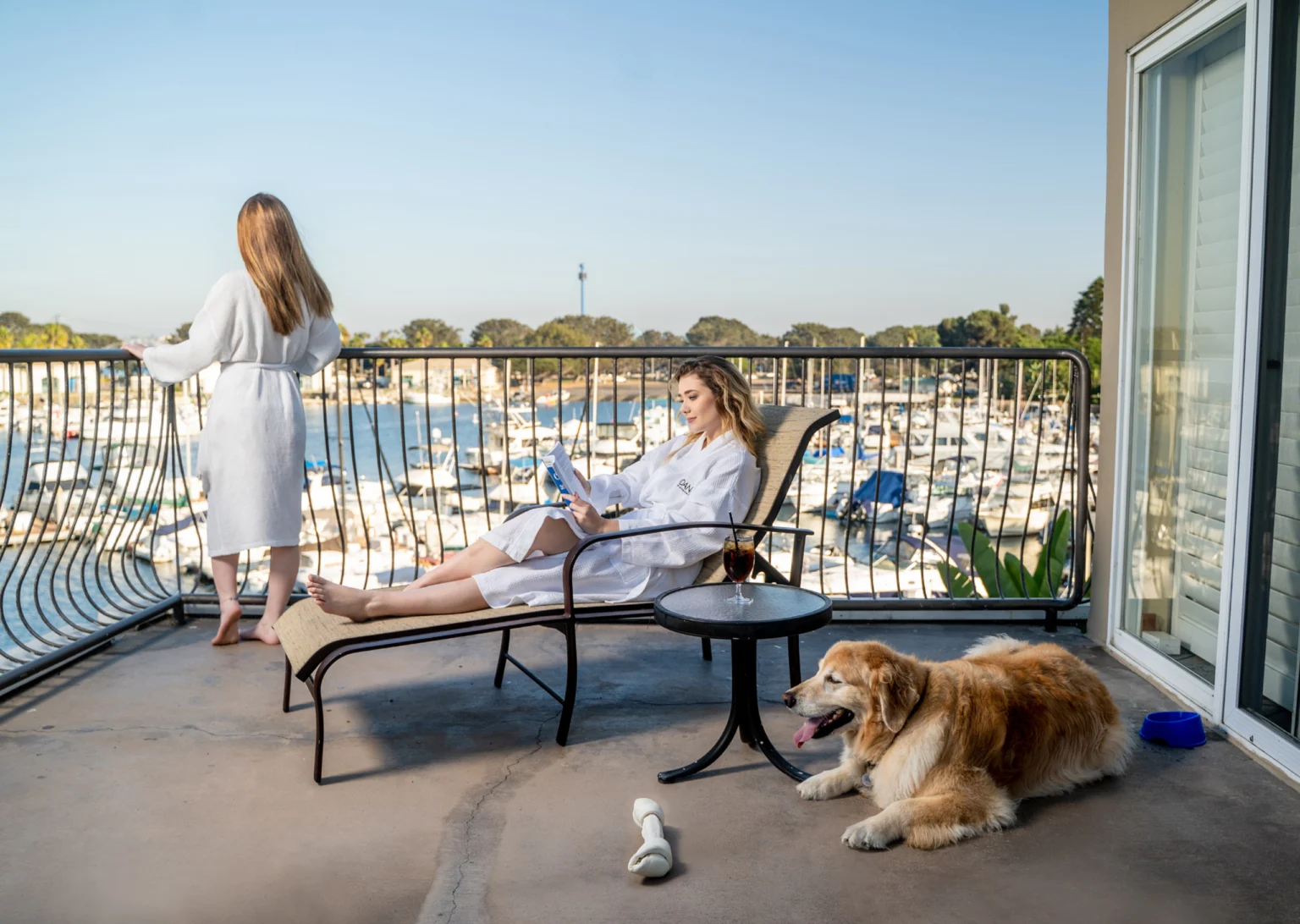 two women relaxing on the balcony of their room with their dog