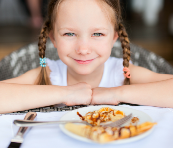 Smiling girl in front of a dinner plate