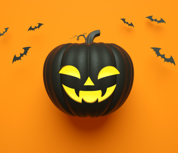 a black pumpkin on an orange background with bats