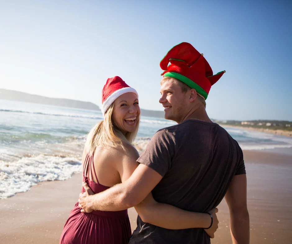 Couple on the beach wearing santa hats