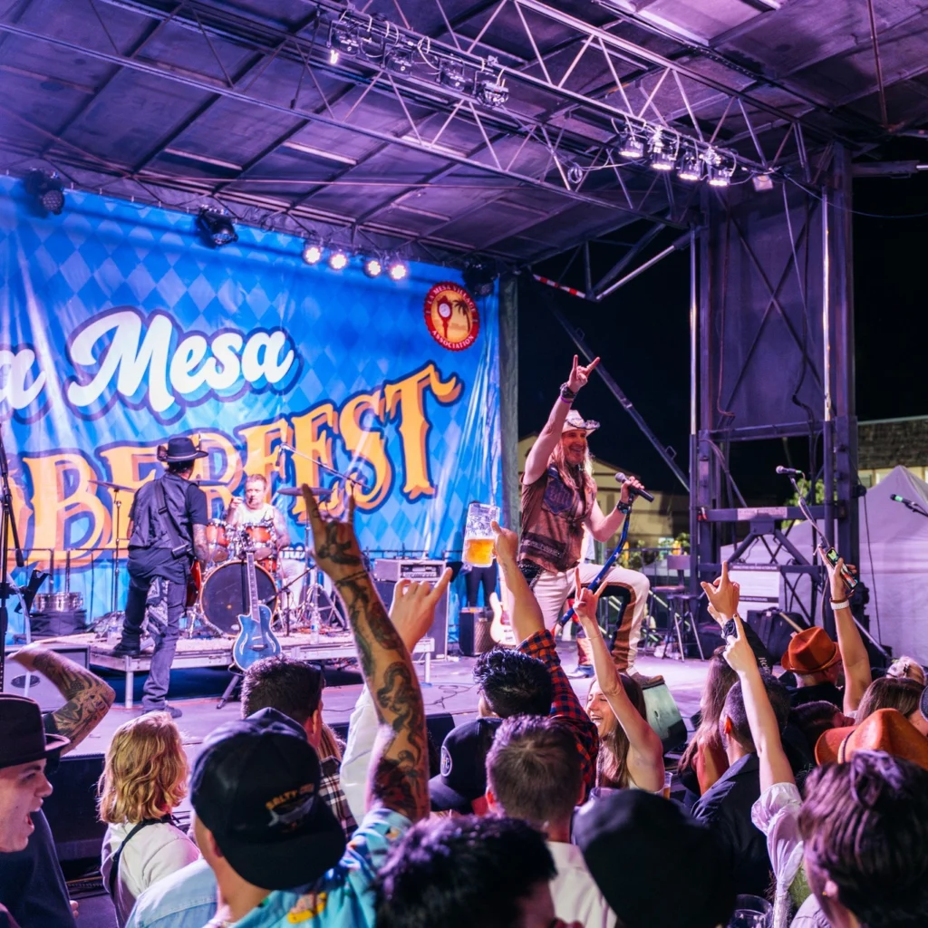 a crowd in front of a stage with a band performing at la mesa oktoberfest