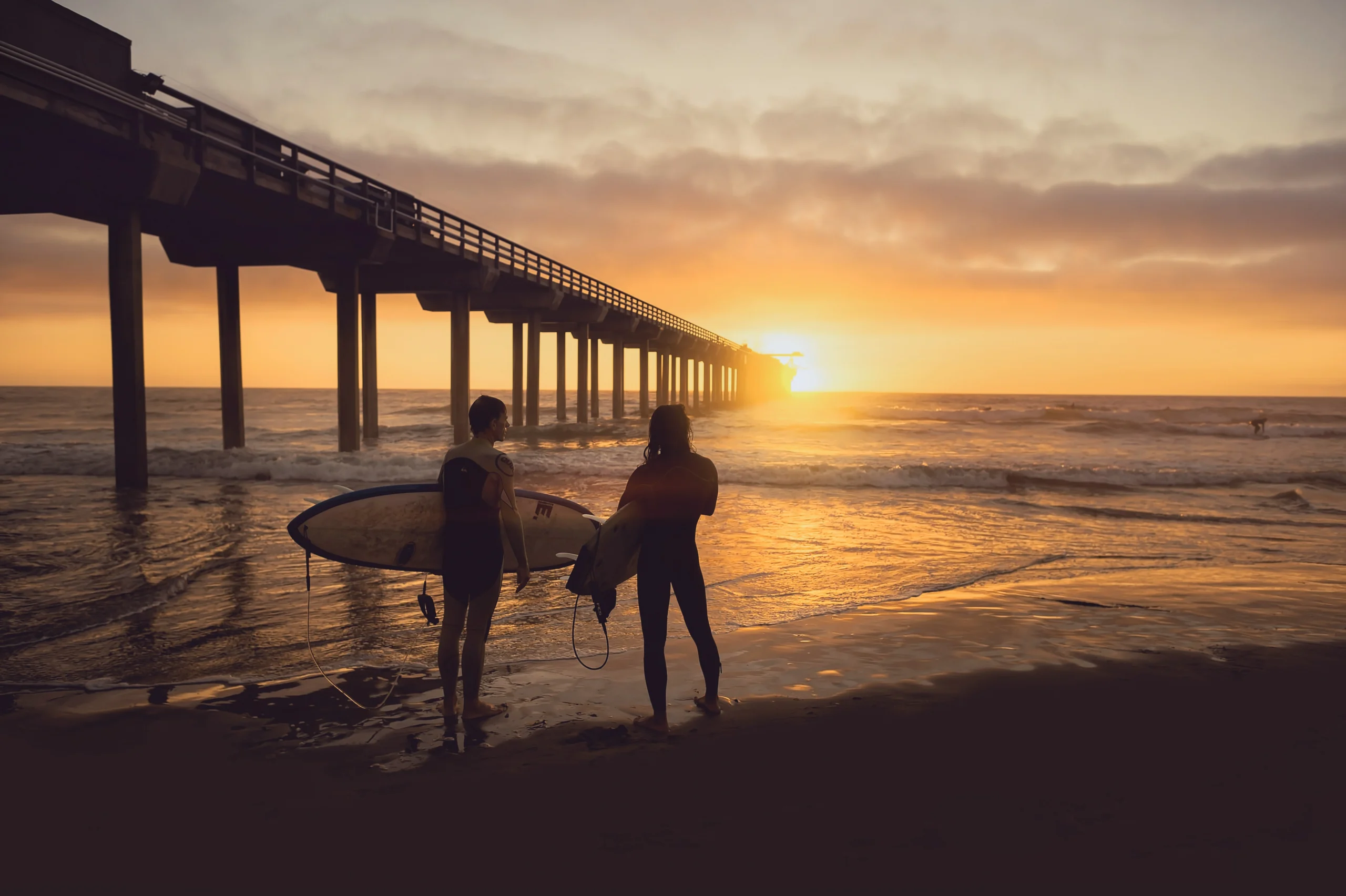 two surfers at sunset at the beach