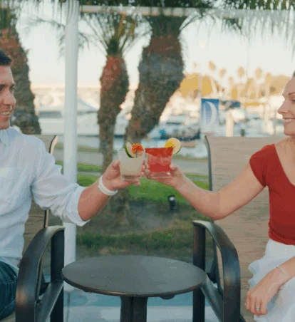 Two people cheersing drinks in front of pool