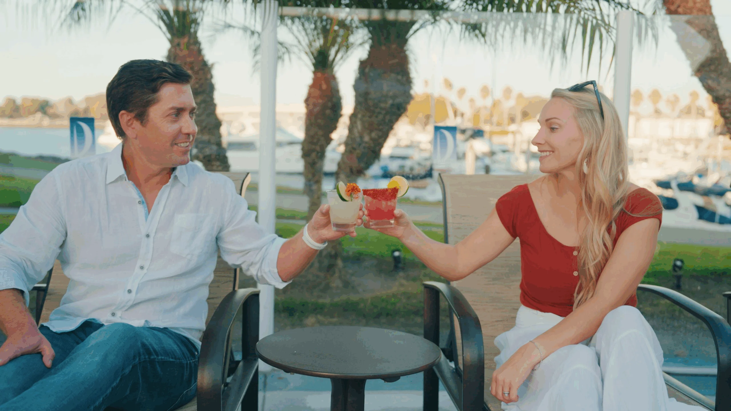 Two people cheersing drinks in front of pool