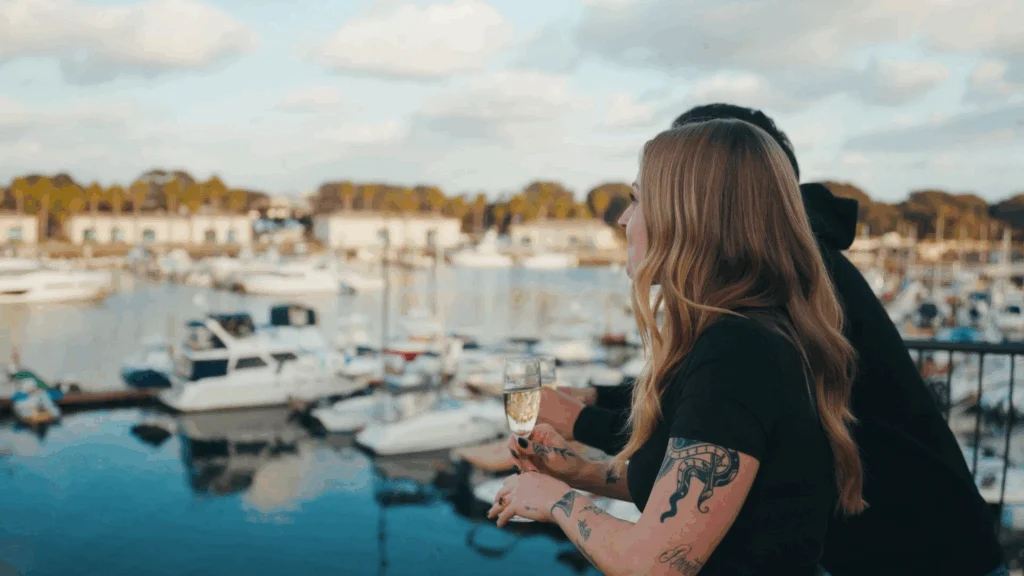 Guests holding champagne off balcony overlooking bay