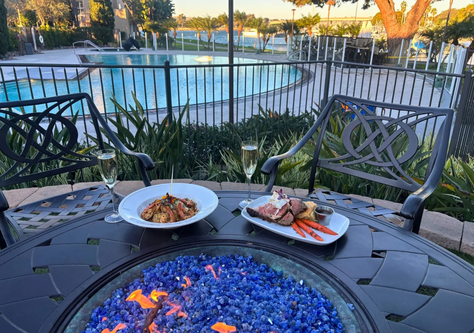 Plates and wine glasses on firepit overlooking pool and bay