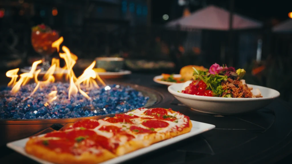 food on a table in front of firepit