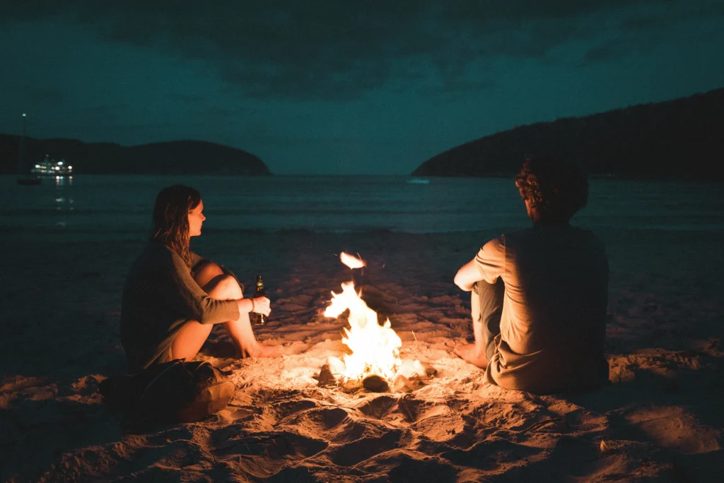 a couple by a fire on the beach