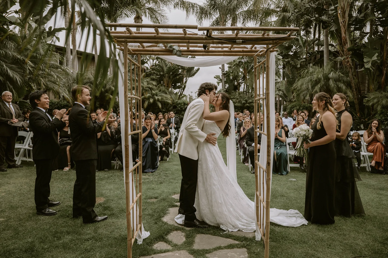 Newlyweds kissing under alter in tropical garden at The dana